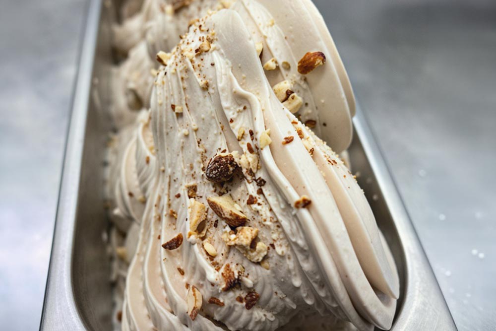 En gelatoglass med hasselnötsmak toppad med hasselnöts kross, fint upplagd i en metallbehållare