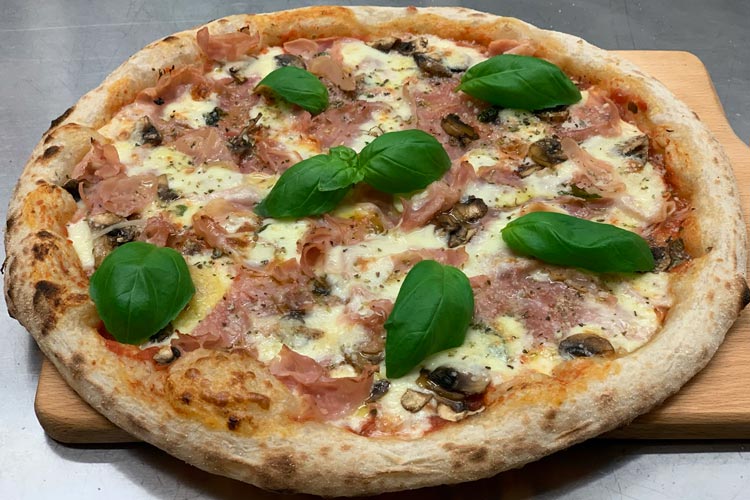 Närbild på Amores napolitanska pizza Capricciosa, med gyllene krispig kant